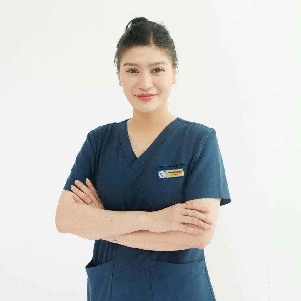 Professional portrait of a smiling female nurse with folded arms in a medical uniform.